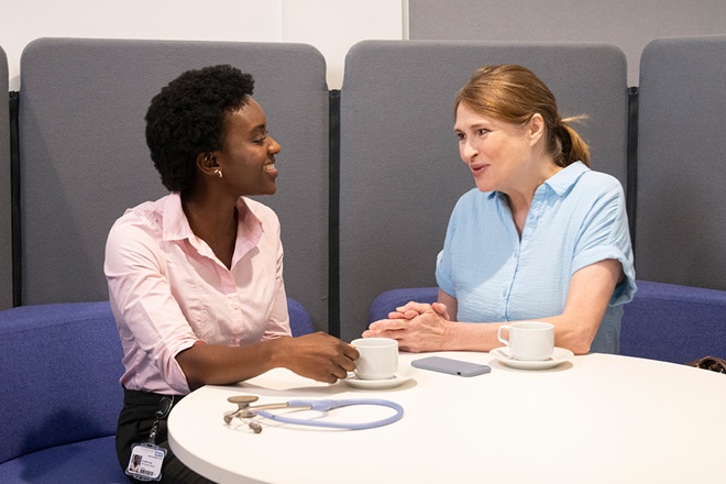 Two female colleagues having a conversation at a round table