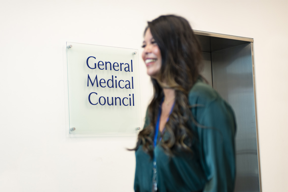 GMC female colleague stood out of focus in front of GMC logo