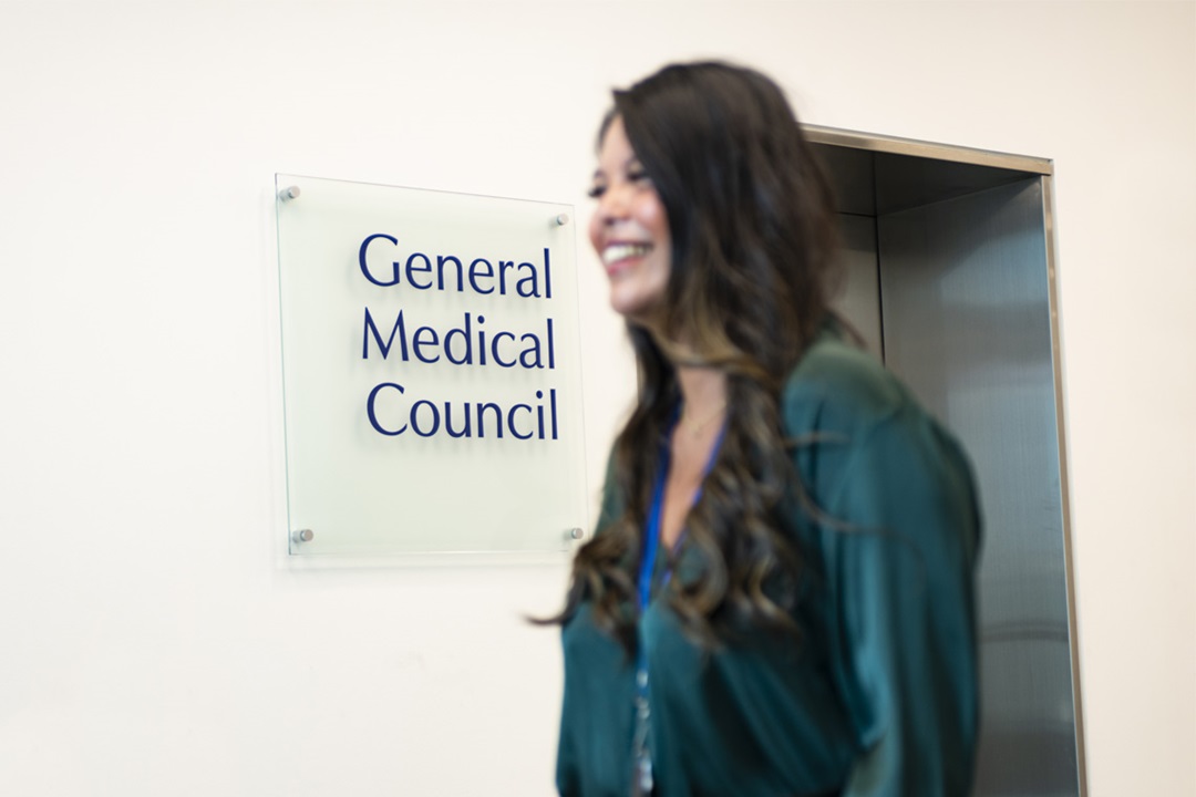 GMC female colleague stood out of focus in front of GMC logo