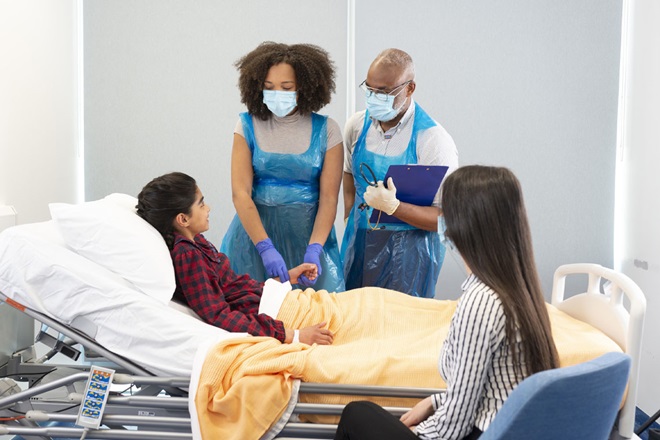 Two medical professionals consulting with a patient in a hospital bed