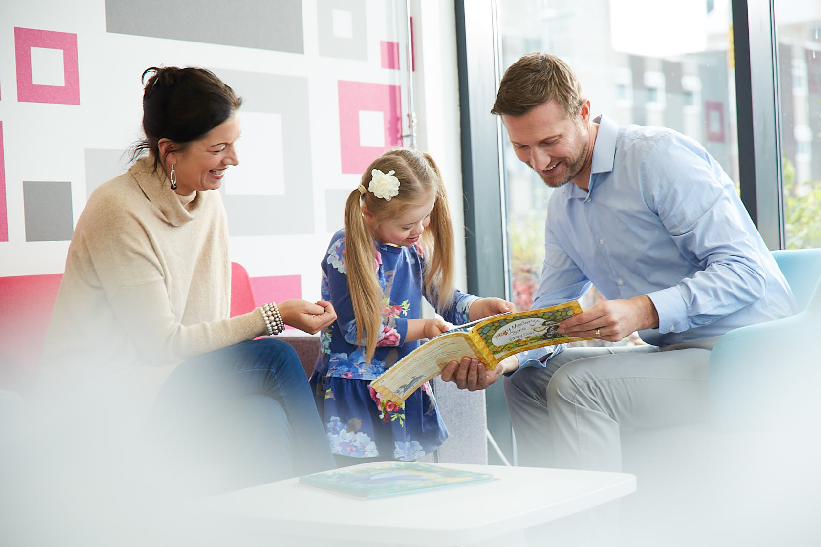 A doctor looking at a book with a child and her mother