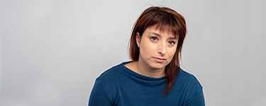 Woman wearing a blue cardigan, head tilted to the side