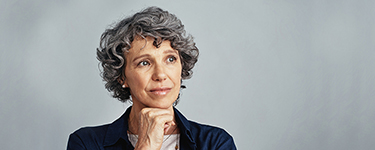 Adult woman wearing a blue jacket, thinking with her hand on her chin