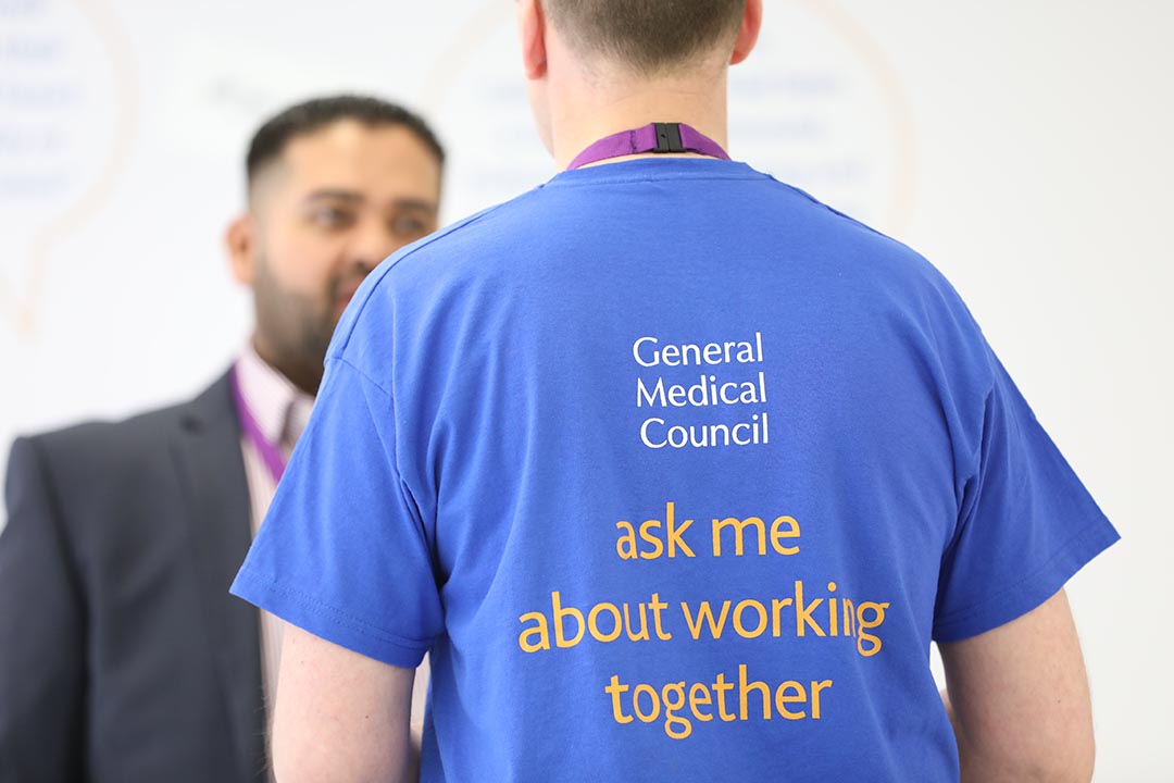 GMC employees talking. T-shirt reads 'General Medical Council: ask me about working together'