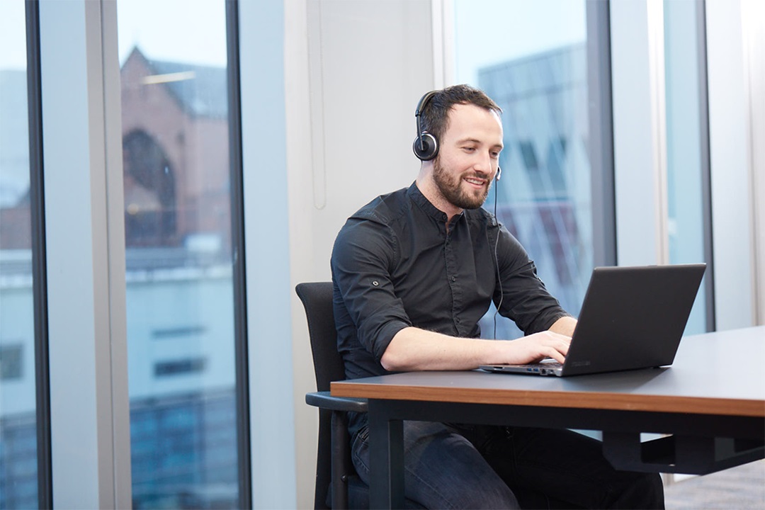 A GMC employee sat at desk with a headset