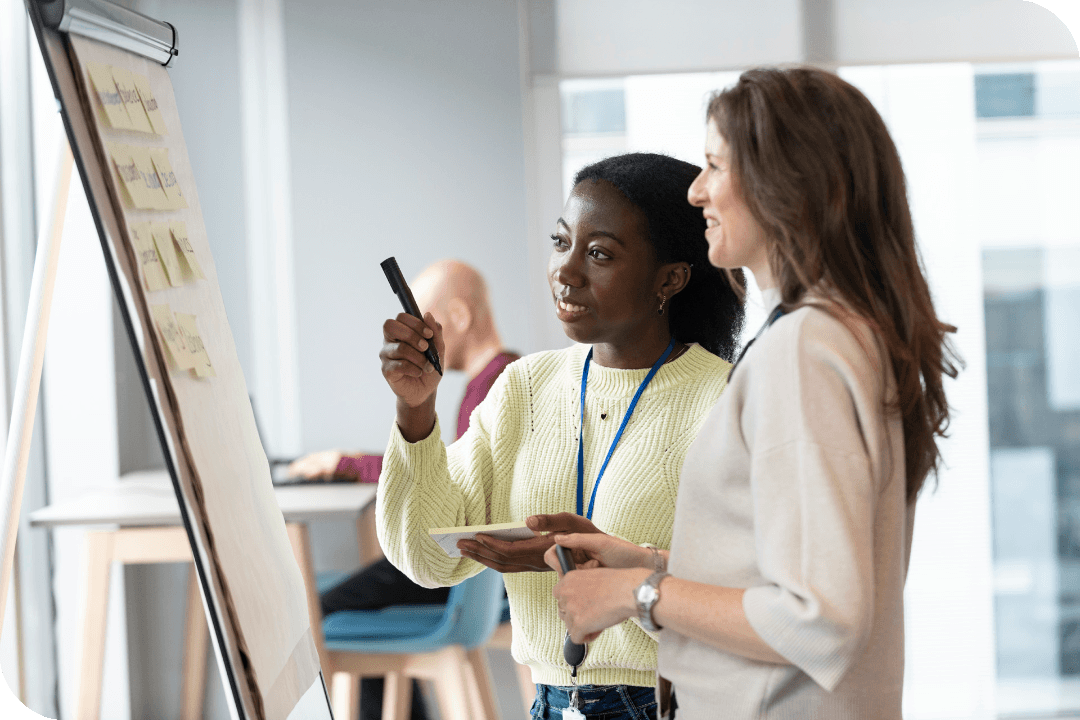 Two members of staff talk at a flipchart