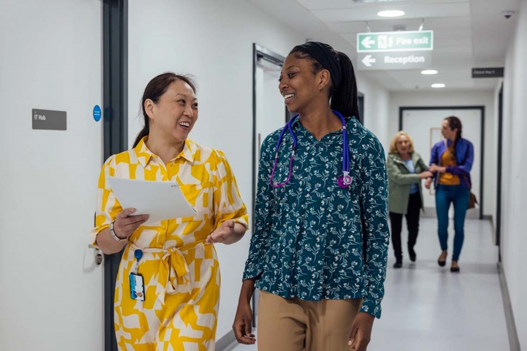 A doctor and a colleague in conversation walking down a hallway