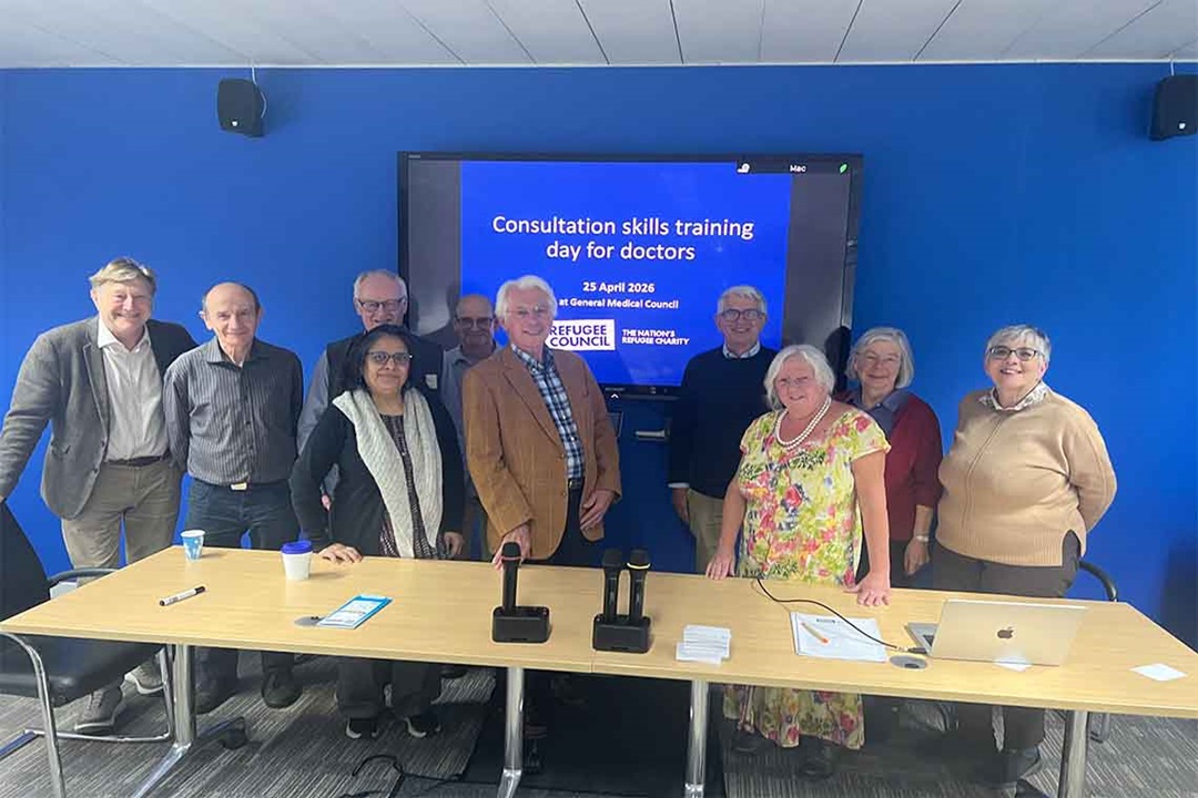 A group of people standing behind a table at the ‘Building Bridges’ event, organised by the Refugee Council. 