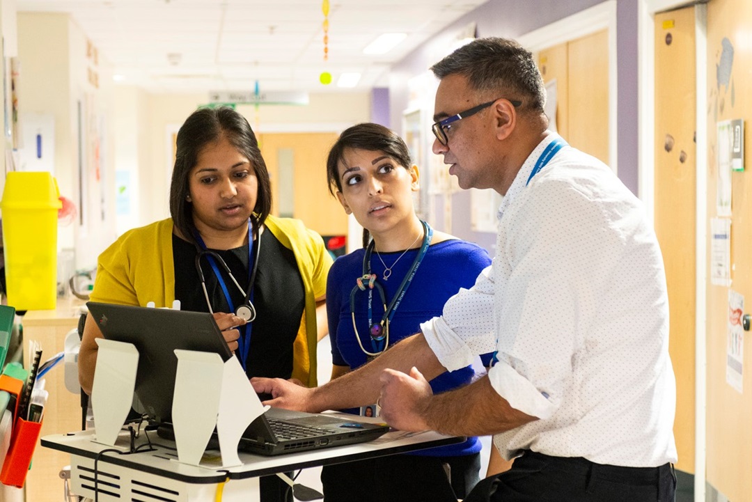 A group of doctors gathered around a computer in the hospital