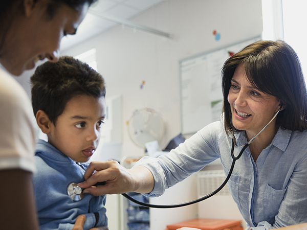 A young boy is examined by a female doctor using a stethoscope