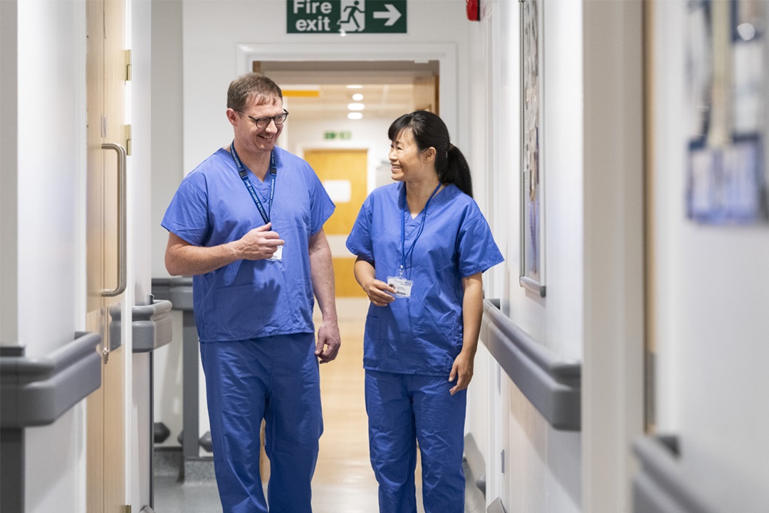 Two anaesthesia associates walking down a corridor in a healthcare setting