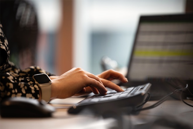 Close up of someone typing on a keyboard in an office setting