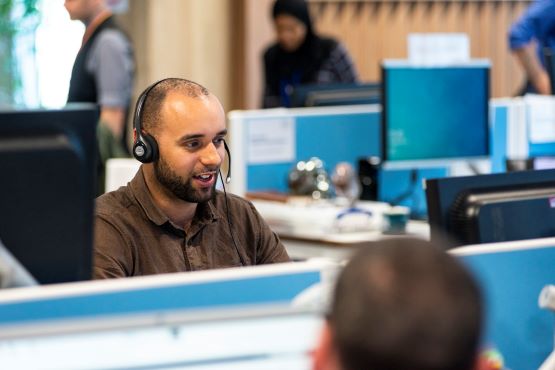 Colleague in the contact centre, taking a call pre pandemic and office closure